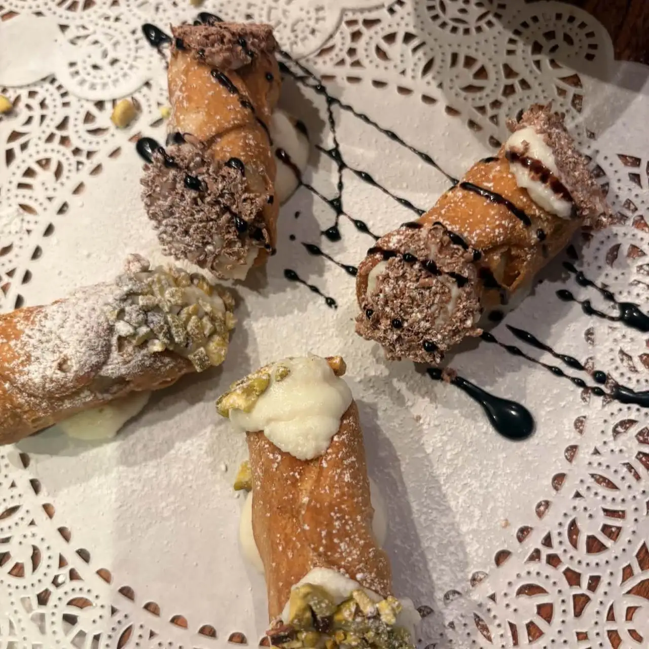 Cannoli with pistachio and chocolate ends on a lace doily